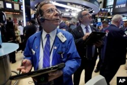 Sal Suarino, left, works with fellow traders on the floor of the New York Stock Exchange, April 28, 2016.