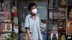 Un homme portant un masque facial pour aider à freiner la propagation du nouveau coronavirus se tient devant une librairie à Bangkok, en Thaïlande, le mardi 26 mai 2020. (AP Photo/Sakchai Lalit)