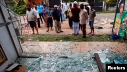 FILE - Muslims stand next to a burnt shop after a clash between Buddhists and Muslims in Aluthgama, Sri Lanka, June 16, 2014. 