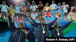 Vatemo Ravouvou, Viliame Mata, and Semi Kunatani, of Fiji, pose with fans after winning the gold medal match against Britain in the mens rugby sevens at the 2016 Summer Olympics in Rio de Janeiro, Brazil, Thursday, Aug. 11, 2016.