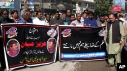 FILE - An employee of a local television channel shows a picture of slain journalist Aziz Memon on his mobile, after a demonstration to condemn his killing, in Hyderabad, Pakistan, Feb. 17, 2020. 