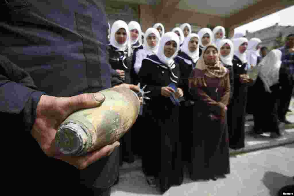 A member of Palestinian security forces loyal to Hamas carries a mortar shell as he explains to girls the dangers of unexploded ammunition, at a school in Khan Younis in the southern Gaza Strip.
