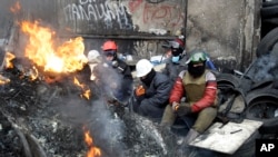 Protesters rest behind a barricade in front of riot police in Kyiv, Ukraine, Jan. 28, 2014.