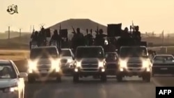 FILE - An image grab taken from a video released by Islamic State group's official Al-Raqqa site via YouTube allegedly shows Islamic State (IS) group recruits riding atop trucks in an unknown location.