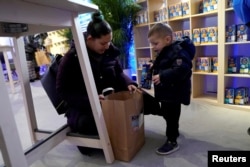 A federal worker left unpaid or furloughed collects a free bag of groceries with a child from Kraft Foods on the 27th day of the partial government shutdown in Washington, U.S., Jan. 17, 2019
