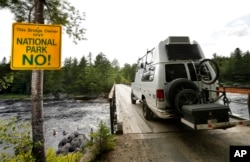 In this Aug. 10, 2017, photo, a visitor crosses a bridge over the Penobscot River's East Branch in the Katahdin Woods and Waters National Monument near Patten, Maine.