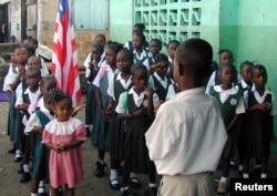 FILE - Liberian students are seen assembled to salute the flag at a Catholic school in the Liberian capital Monrovia.