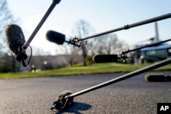 FILE - Members of the media with microphones wait for President Donald Trump to speak on the South Lawn of the White House in Washington, March 13, 2018.