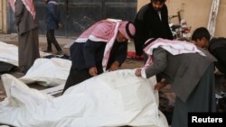 Warga berusaha mengidentifikasi jenazah di rumah sakit menyusul serangan udara oleh pasukan Suriah di Raqqa (25/11). (Reuters/Nour Fourat)
