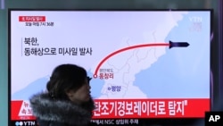 A woman at a train station in Seoul walks by a TV screen showing a news report about North Korea's missile test, March 6, 2017.