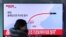 A woman at a train station in Seoul walks by a TV screen showing a news report about North Korea's missile test, March 6, 2017.