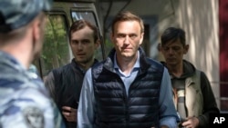 FILE - Russian opposition leader Alexei Navalny, center, arrives at court after his arrest during a protest in Moscow, Russia, May 11, 2018.