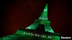 FILE - Menara Eiffel disinari lampu hijau dengan tulis "Paris Agreement is Done" atau "Perjanjian Paris Sudah Selesai" untuk merayakan Konferensi Perubahan Iklim PBB di Paris.