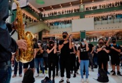 Protesters wearing masks in defiance of a recently imposed ban on face coverings perform at a shopping mall in Hong Kong, Oct.13, 2019.