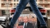A placard featuring an image of Russian President Vladimir Putin and reading "We are with him for the sovereignty of Russia! And you?" is seen left in front of the Russian State Duma building in central Moscow.