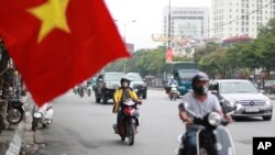 FILE - People wearing face masks to help curb the spread of the coronavirus ride mopeds in Hanoi, Vietnam on Thursday, Aug. 6, 2020. 