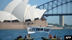 Anggota LSM lingkungan hidup Greenpeace membentangkan spanduk bertuliskan “#LET THEM STAY” (Biarkan Mereka Tinggal), di depan Gedung Opera di Sydney, Australia, 14 Februari 2016.