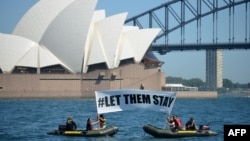 Members of the environmental group Greenpeace hold up a sign that reads "#LET THEM STAY" in front of the Opera House in Sydney, Australia, Feb. 14, 2016. A hospital in Brisbane has refused to send an asylum-seeker baby back to detention in Nauru as momentum builds across the country against offshore Pacific camps for used by the government for processing refugees who try to get to Australia. 