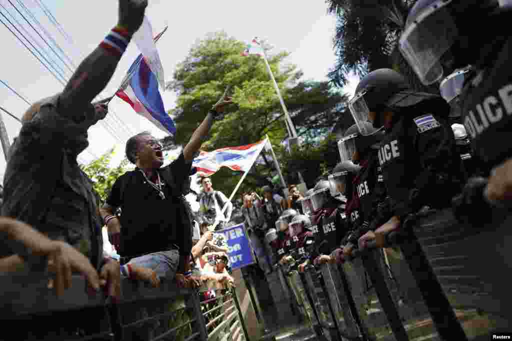 Anti-government protesters gesture towards riot police outside the headquarters of the ruling Puea Thai Party of Prime Minister Yingluck Shinawatra in Bangkok, Nov. 29, 2013. 