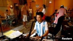 Zu Wenbao, 23, plays the keyboard during a practice session with his band Star Kids, who like him are all adults with autism spectrum disorder. (REUTERS/Tingshu Wang)