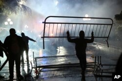 A protester removes a fence near the Parliament building during clashes with national police in Tirana, May 13, 2019.
