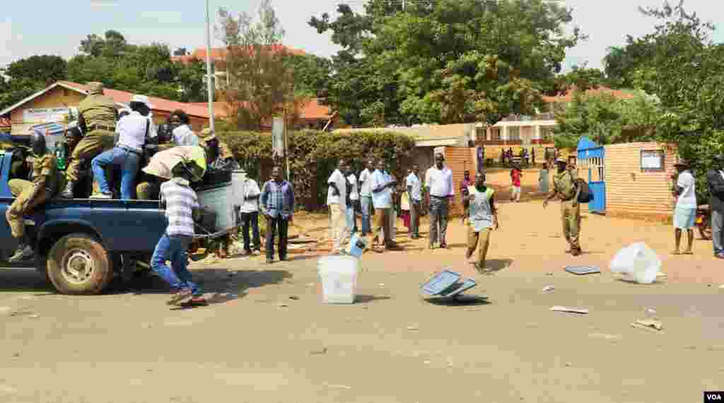Police in Kampala leave a polling place with empty ballot boxes, spilling many boxes onto the road as they hastily departed. E. Paulat/VOA