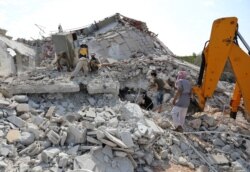 Members of the Syrian Civil Defense (White Helmets) search for victims amidst the rubble of a building that collapsed during reported airstrikes by pro-regime forces in the village of Beinin in the northern Idlib province, Aug. 20, 2019.