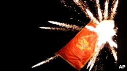 The Montenegrin flag flying from the Montenegrin Embassy, is targeted with fireworks by Serbian ultra-nationalists during a protest against a religion rights law adopted by Montenegro's parliament last month, during a mass protest in Belgrade, Serbia, Jan