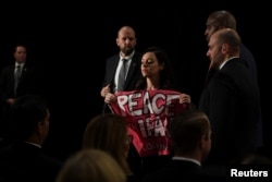 A protester holding a sign that says "Peace with Iran" is escorted out of the room during U.S. Secretary of State Mike Pompeo's remarks during the United Against Nuclear Iran Summit on the sidelines of the U.N. General Assembly in New York, Sept. 25, 2018.