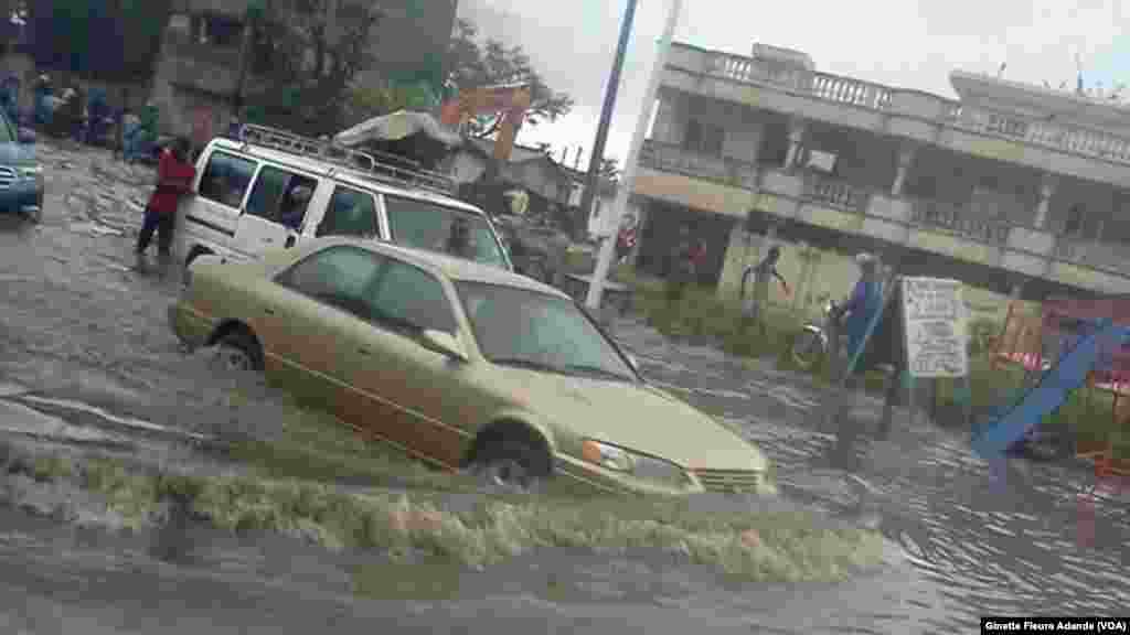 Quasiment impossible de faire les courses sans entrer dans l’eau dans les quartiers avoisinant le stade Général Mathieu Kerekou, à Cotonou, Benin, 8 octobre 2016. VOA/Ginette Fleure Adande