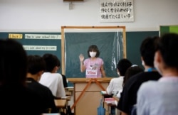 A student makes a presentation behind a plastic sheet to prevent the coronavirus disease infection during an english class at Takanedai Daisan elementary school in Funabashi, east of Tokyo, Japan July 16, 2020. (REUTERS/Kim Kyung-Hoon)