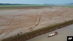FILE - Fishermen push a boat in the Aleixo Lake amid a drought in Manaus, Amazonas state, Brazil, Sept. 24, 2024.