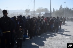 FILE - Migrants and refugees wait in a queue to be allowed to pass from the northern Greek village of Idomeni to southern Macedonia, Nov. 9, 2015.