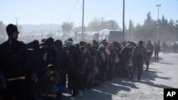 Migrants and refugees wait in a queue to be allowed to pass from the northern Greek village of Idomeni to southern Macedonia, Nov. 9, 2015. 