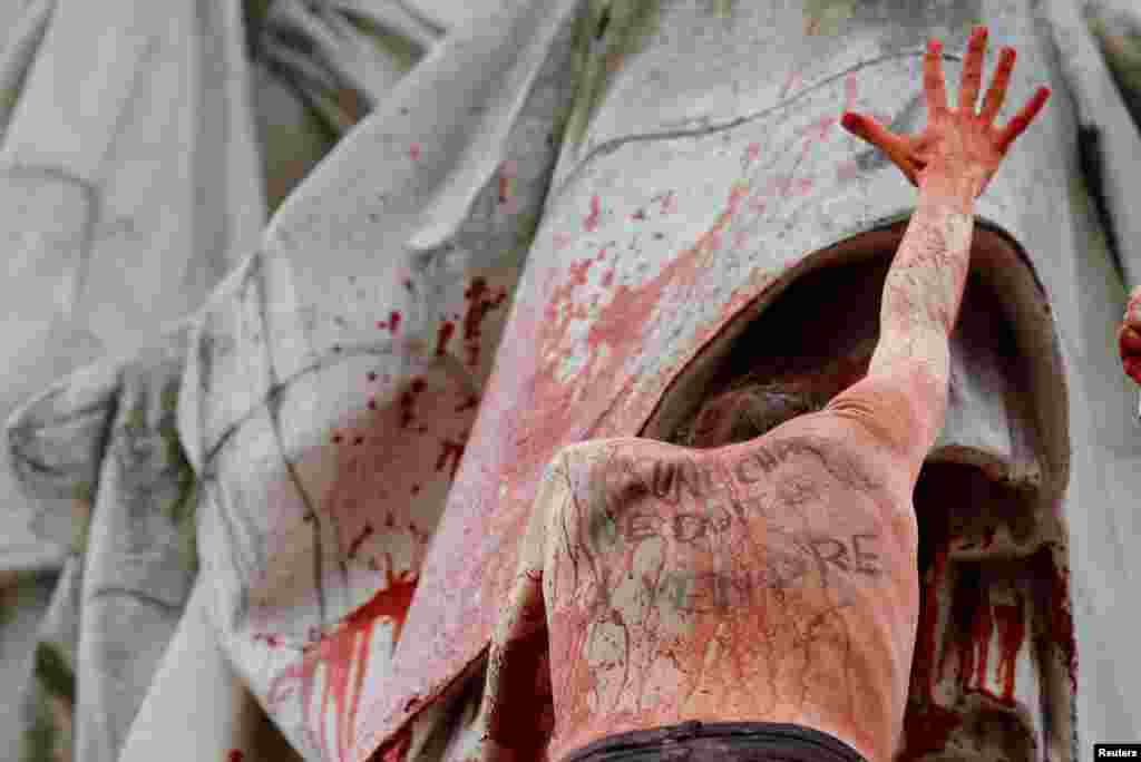 A woman with the message written on her back, &quot;No flesh should be for sale&quot; stands on the statue at the Place de la Republique during a protest to highlight the pay disparity between women and men, in Paris, France, March 8, 2019.