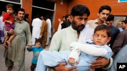 A man carries a child injured from an earthquake, in Peshawar, Pakistan, Oct. 26, 2015.