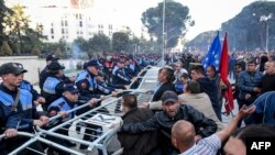 បាតុករ​ព្យាយាម​រើ​របាំង​ការពារ​នៅ​ខាង​ក្រៅ​អគារ​រដ្ឋាភិបាល​ ក្នុង​ពេល​បាតុកម្ម​មួយ​នៅ​ក្នុង​ក្រុងទីរ៉ាណា (Tirana) ប្រទេស​អាល់បានី កាលពី​ថ្ងៃទី១១ ខែឧសភា ឆ្នាំ២០១៩។