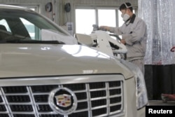 FILE - A staff member works at a service center for repairing Cadillac cars at its dealership in Beijing, China, March 14, 2016.