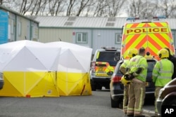 Fire officers stand inside a cordon at the vehicle recovery business "Ashley Wood Recovery" in Salisbury, England, March 13, 2018.