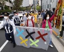 FILE - People protest the Tokyo 2020 Olympics amid the coronavirus outbreak, around Olympic Stadium (National Stadium) as an Olympic test event for athletics is held inside the venue in Tokyo, Japan, May 9, 2021, in this photo taken by Kyodo.