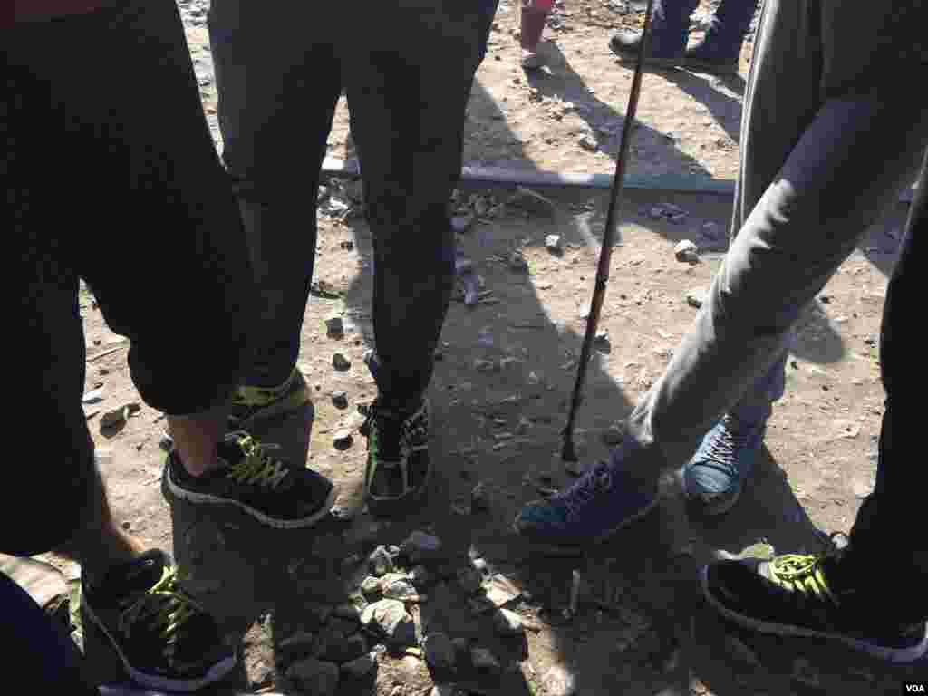 Demonstrating dangers for small children living in this camp, young men point out a dead snake on the ground, nearby Idomeni, Greece, March 30, 2016. (Photo - H. Murdock/VOA)