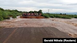 People stand on the other side of a road destroyed by tropical storm Ana, along M1 Chikwawa road, Malawi, Jan. 26, 2022, in this screen grab obtained from a social media video.