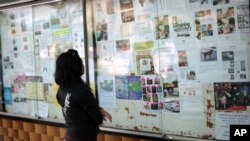This picture taken on January 19, 2011 shows a young woman reading advertisements for "maids wanted" outside a shopping mall in Kuala Lumpur.