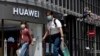 Residents wearing face masks to protect against the coronavirus walk past a Huawei retail store in Beijing, May 18, 2020.