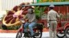 FILE PHOTO - A Cambodian police officer, right, talks with a motorcycle taxi driver next to a floral decoration set up ahead of the ASEAN Summit along a road in Phnom Penh, Cambodia, Sunday, April 1, 2012. 