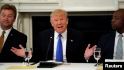 Seated between Senators Dean Heller of Nevada, left, and Tim Scott of South Carolina, President Donald Trump meets with Senate Republicans to discuss health care legislation at the White House in Washington, July 19, 2017.