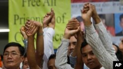 Members of the opposition Cambodia National Rescue Party (CNRP), raise joined hands for photographs at their party headquarters in Phnom Penh, Cambodia, Friday, May 27, 2016. A Cambodian court on Friday convicted three military commandos of beating up two CNRP lawmakers outside the parliament last year, and sentenced them to one year each in prison. The legislators' lawyer called the punishment too lenient. (AP Photo/Heng Sinith)