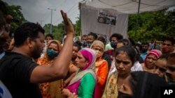 A man tries to calm protesters down as they demonstrate outside a crematorium where a 9-year-old girl was, according to her parents and protesters, raped and killed in New Delhi, India, Aug. 5, 2021. 