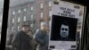Ukrainians look at a "Wanted" notice for fugitive Ukrainian President Victor Yanukovych plastered on the window of a car near Independent Square in Kyiv on February 24, 2014.