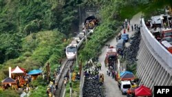 This photo shows rescue workers at the site where a train derailed inside a tunnel in the mountains of Hualien, eastern Taiwan on April 2, 2021. (Photo by Sam Yeh / AFP)